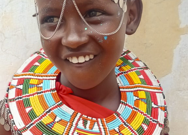 A young girl dressed in a red shuka and traditional beads for a dance display